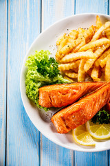 Fried salmon, French fries and vegetables