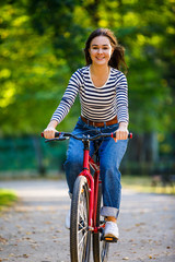 Fototapeta premium Urban biking - woman riding bike in city park