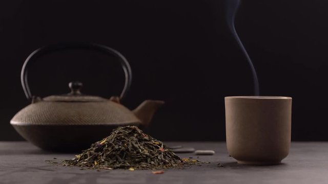un tas de feuilles de th&eacute; avec une tasse et une th&eacute;i&egrave;re en fond