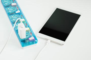 Digital tablet charging with extension socket on white background