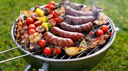Grilled food. Various grilled products: Grilled sausages, meat and vegetable skewers, bacon and vegetables on the grill plate, outside. Barbecue, bbq