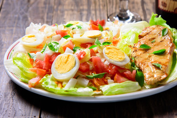 colorful fresh vegetable salad with lettuce eggs tomatos with grilled chicken breast on a wooden table with grilled chicken breast on a wooden table