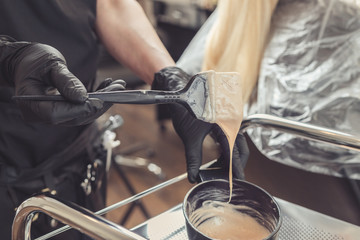 Hair stylist hands preparing a dye in a container