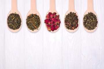 Set of dry herbal teas in wooden spoons on a white background. View from above