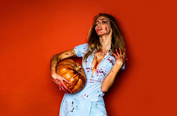 Woman as sexy vampire - halloween concept. Scary bloody zombie girl with pumpkin. Woman with red...