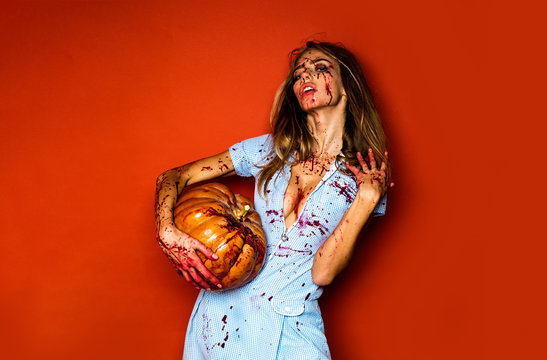 Woman as sexy vampire - halloween concept. Scary bloody zombie girl with pumpkin. Woman with red blood and with blond hair.