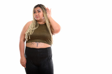 Studio shot of young fat Asian woman standing while listening