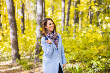 Nature, season and people concept - young woman holding sunglasses at the autumn park