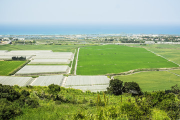 Agriculture scenic view of green fields and greenhouses, blue sea and sky in Israel