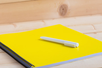 Yellow notepad with pen on wooden background