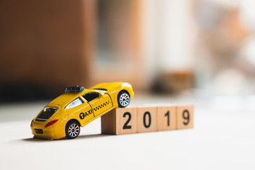 Yellow taxi run around wooden block year 2019 using as transportation concept