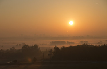 Bright beautiful dawn, the sun rises over the city, the light passes through the fog
