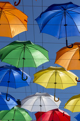 Soaring colored umbrellas against a blue sky