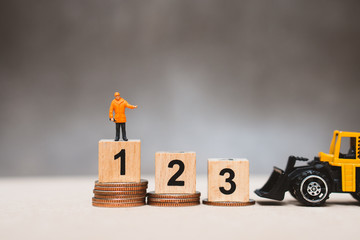 Miniature people, technician standing on podium and stack coins using as business competition and...
