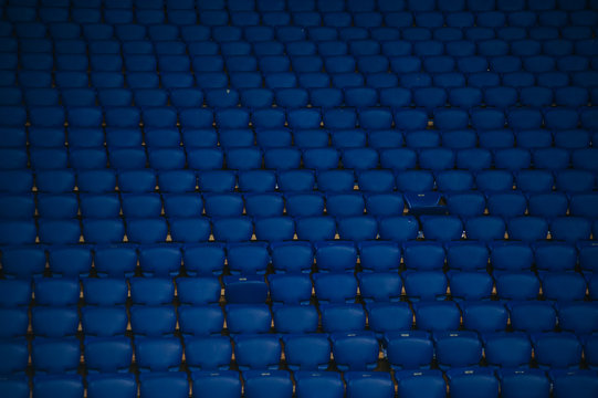 Blue empty seats at a football stadium. Yellow stairs with a number of sectors.