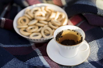 White porcelain cup with black tea and russian bagels at plaid, autumn time.