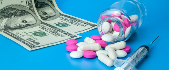 Syringe, dollars and pink pills on a bright blue background.