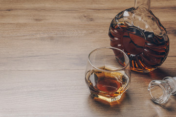 a glass of bourbon whiskey and a whiskey decanter on the wooden table