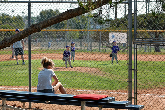 Girl On The Bleachers Watching Little Boys Play T-ball.