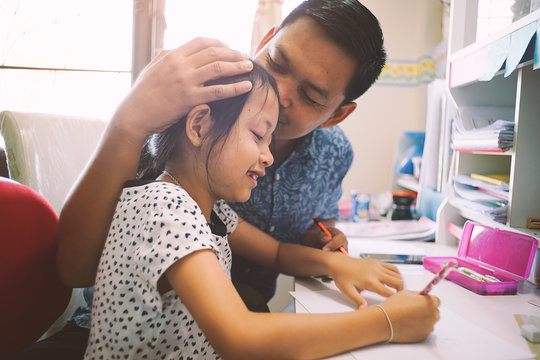 Young Daughter And Her Father Helping Homework School Project At Home.