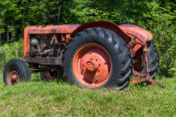 Obraz premium Old unused tractor in grass field