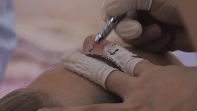 Close-up of cosmetologist making microblading procedure.