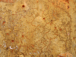 An old rough yellow ochre colored cracked faded stained painted plaster wall texture with red and...