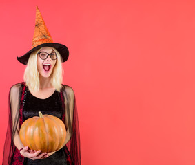 Winking sexy witch in glasses with magic pumpkin. Happy Halloween witch with jack-o-lantern. Halloween costume party. Halloween decor. Halloween wizard with Magic Pumpkin. Beautiful girl with Pumpkin.