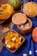 Baked pieces of pumpkin with feta cheese in a wooden bowl on the table. Autumn meal