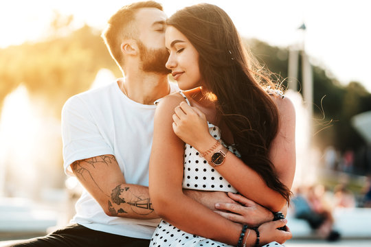 Handsome guy kissing beautiful girls kissing on the background of a fountain