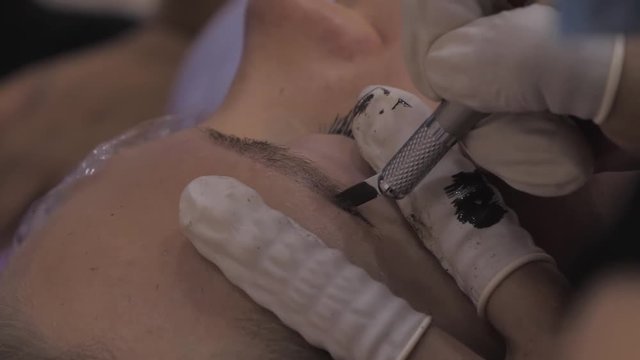 Close-up of cosmetologist making microblading procedure.