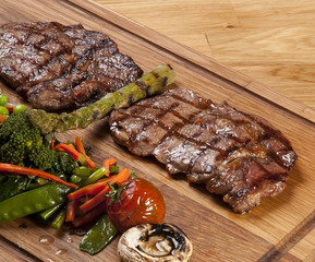 Meat steak on the wooden board with vegetables