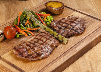 Meat steak on the wooden board with vegetables