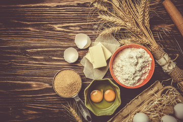 Fototapeta na wymiar Baking concept - baking ingredients butter, flour, sugar, eggs on rustic wood background, top view