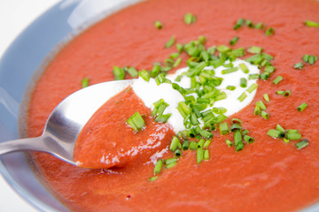 Beetroot cream soup decorated with yogurt and chives being eaten with a spoon