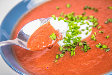 Beetroot cream soup decorated with yogurt and chives being eaten with a spoon