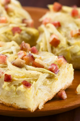 Fresh homemade traditional German Zwiebelkuchen onion cake savory baked pastry or pie made of yeast dough topped with onion, bacon, eggs, cream (Selective Focus one third into the first cake piece)
