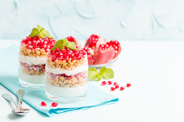 Pomegranate parfait - sweet organic layered dessert with granola flakes, yogurt and ripe fruit seeds.