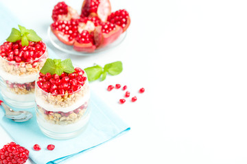 Pomegranate parfait - sweet organic layered dessert with granola flakes, yogurt and ripe fruit seeds.