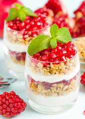 Pomegranate parfait - sweet organic layered dessert with granola flakes, yogurt and red ripe fruit seeds.
