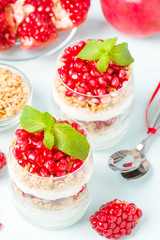 Pomegranate parfait - sweet organic layered dessert with granola flakes, yogurt and red ripe fruit seeds.