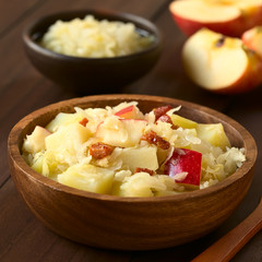 Potato, sauerkraut and apple salad with fried bacon served in wooden bowl, photographed with...
