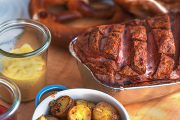 Frischer bayerischer Leberkäse und Breze aus dem Ofen mit Bratkartoffeln im Biergarten Wirtshaus zum Essen