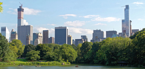 Fototapeta premium NEW YORK, USA - August 5, 2014: Pond in the central park in NYC. Central Park and Manhattan Skyline. Midtown Manhattan skyline viewed from Central Park