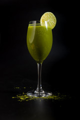 green cocktail with slice of lime and wasabi on black background