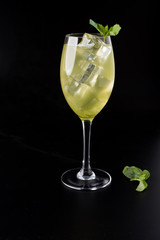 yellow cocktail with ice and mint on black background