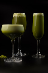 three glasses with green tea cocktails on black background