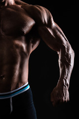 Fototapeta na wymiar Muscular man's torso on black background with backlight