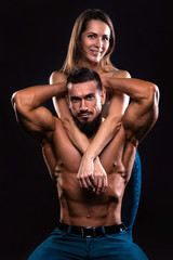 Fitness couple on a black background looking forward and smiling