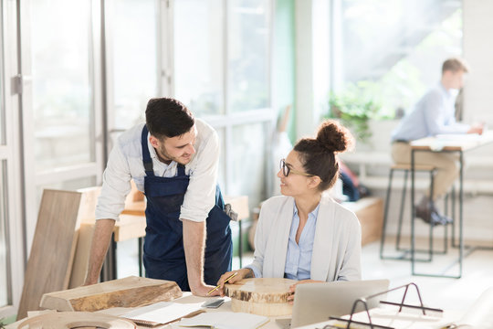 Two engineers consulting about new wood materials while choosing suitable one for new collection of furniture